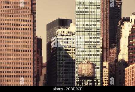 New York City vielfältige Architektur mit altem hölzernen Wasserturm im Vordergrund, retro farbiges Bild, USA. Stockfoto