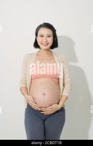 Schwangere Frau streichelt ihren Bauch auf weißem Hintergrund Stockfoto