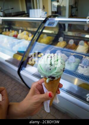 Hand hält ein Eis vor einem Eis Cremegeschäft Stockfoto