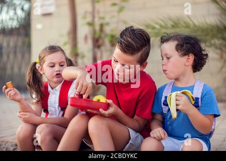 Schüler, die einen Snack im Freien. Kinder, Bildung und Ernährung Konzept Stockfoto