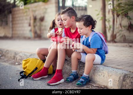 Schüler, die einen Snack im Freien. Kinder, Bildung und Ernährung Konzept Stockfoto