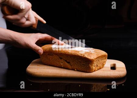 Hausgemachtes graues Brot auf schwarzem Hintergrund. Foto im Abschnitt. Stockfoto
