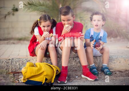 Schüler, die einen Snack im Freien. Kinder, Bildung und Ernährung Konzept Stockfoto