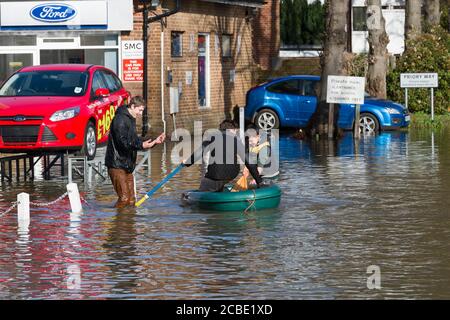 Boys peddeln ein Boot durch überflutete Slough Road im Dorf Datchet, Berkshire, nachdem die Themse an ihren Ufern platzte. Datchet, Berkshire, Großbritannien. Februar 2014, 10 Stockfoto