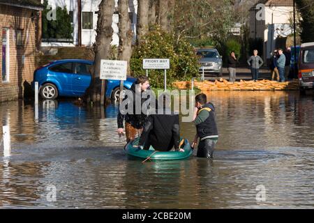 Boys peddeln ein Boot durch überflutete Slough Road im Dorf Datchet, Berkshire, nachdem die Themse an ihren Ufern platzte. Datchet, Berkshire, Großbritannien. Februar 2014, 10 Stockfoto