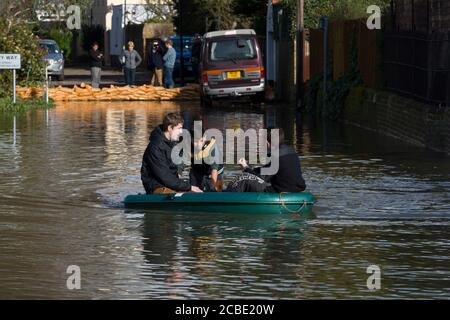 Boys peddeln ein Boot durch überflutete Slough Road im Dorf Datchet, Berkshire, nachdem die Themse an ihren Ufern platzte. Datchet, Berkshire, Großbritannien. Februar 2014, 10 Stockfoto