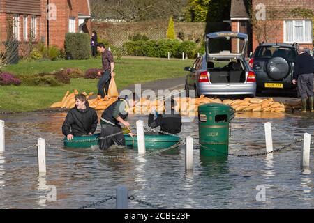 Boys peddeln ein Boot durch überflutete Slough Road im Dorf Datchet, Berkshire, nachdem die Themse an ihren Ufern platzte. Datchet, Berkshire, Großbritannien. Februar 2014, 10 Stockfoto