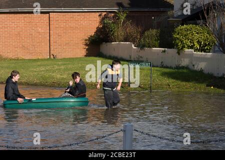 Boys peddeln ein Boot durch überflutete Slough Road im Dorf Datchet, Berkshire, nachdem die Themse an ihren Ufern platzte. Datchet, Berkshire, Großbritannien. Februar 2014, 10 Stockfoto