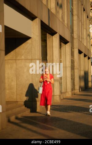 Verwischen Sie die Menschen, die in der sonnigen Straße der Stadt spazieren Stockfoto