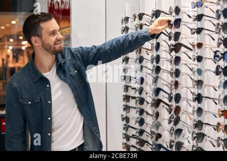 Handsome bärtigen Mann in der Mode Casual Clohes ist die Wahl Brille in Optik Store.close up Foto. Lifetsyle, Freizeit, Freizeit Stockfoto