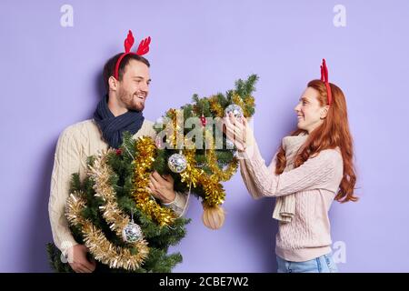 Zeit für Winterferien, junge schöne Paar fröhlich Zeit zu Hause verbringen, Dekoration Weihnachtsbaum, isoliert Foto auf violettem Hintergrund, glücklich Stockfoto