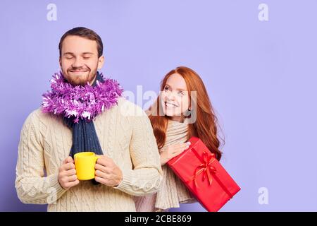 Charming sehr großen Mann mit dicken Bart, in gestrickten warmen Pullover gekleidet, hält Tasse heißen Tee, immer bereit, Weihnachtsgeschenk zu erhalten, schließen Auge Stockfoto