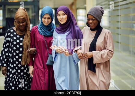 Diverse muslimische multiethnische weibliche Vertreter, die an der internationalen Konferenz teilnehmen, posieren in der Lobby des Geschäftszentrums Stockfoto