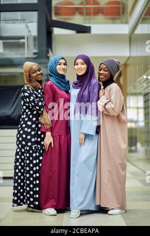 Diverse muslimische multiethnische weibliche Vertreter, die an der internationalen Konferenz teilnehmen, posieren in der Lobby des Geschäftszentrums Stockfoto