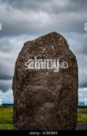 Ein hoher stehender Stein mit der eingravierten Wortschottischen Markierung Die Grenze zwischen Schottland und England mit dramatischen Wolken Die Entfernung Stockfoto