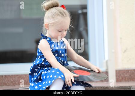 Kleines Mädchen mit Platten auf der Treppe sitzen Stockfoto