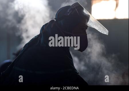 (200813) -- WEST JAVA, 13. August 2020 (Xinhua) -- EIN Arbeiter, der eine Gesichtsmaske und einen Gesichtsschutz tragen, arbeitet in einer Cracker-Fabrik in Depok, West Java, Indonesien, 13. August 2020. Indonesien wird 9 Millionen kleine und mittlere Unternehmen (KMU) mit Working Capital unterstützen, um ihnen zu helfen, Unternehmen wiederzubeleben, die von der neuartigen Coronavirus-Pandemie zerstört wurden, sagte ein Minister hier am Mittwoch. ( Xinhua/Agung Kuncahya B.) Stockfoto