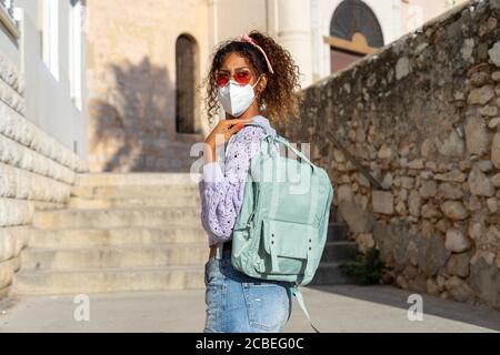 Porträt einer attraktiven jungen schwarzen Frau, die mit Rucksack und Maske läuft. Sehenswürdigkeiten Stockfoto