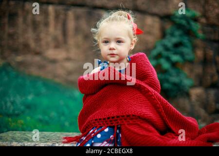 Das kleine Mädchen ist in eine rote Wolldecke gehüllt. Stockfoto