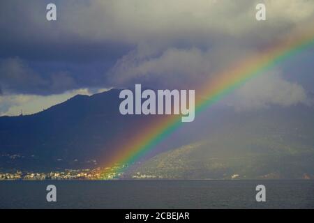 Regenbogen über dem Mittelmeer. Fotografiert in Poros ist ein kleines griechisches Inselpaar im südlichen Teil des Saronischen Golfs, Griechenland im November Stockfoto