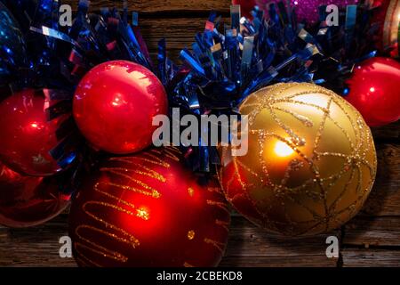 Neujahr und Weihnachten Dekoration Kugeln Nahaufnahme Ansicht auf Holzhintergrund. Goldene, blaue und rote Kugeln mit blauen Zierbändern Stockfoto
