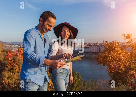Junges Paar, das bei Sonnenaufgang die richtige Richtung auf der Karte vom Gellert-Hügel in Budapest sucht Stockfoto