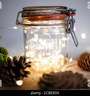 Weicher Fokus von Weihnachtslichtern in einem Glas umgeben Mit Pinienzapfen Stockfoto