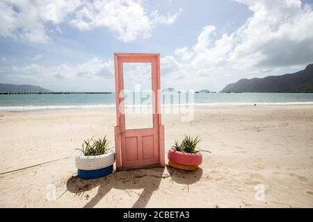 Blick auf pinke Tür mit Pflanzen in Reifen auf beiden Seiten an der Küste in Con Dao, Vietnam Stockfoto