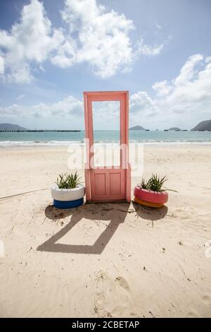 Blick auf pinke Tür mit Pflanzen in Reifen auf beiden Seiten an der Küste in Con Dao, Vietnam Stockfoto