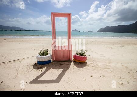 Blick auf pinke Tür mit Pflanzen in Reifen auf beiden Seiten an der Küste in Con Dao, Vietnam Stockfoto