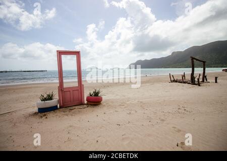 Blick auf pinke Tür mit Pflanzen in Reifen auf beiden Seiten an der Küste in Con Dao, Vietnam Stockfoto