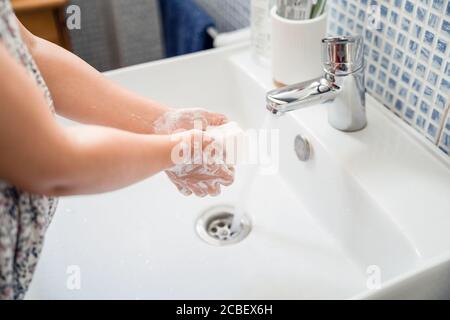 Kleines Mädchen wäscht die Hände mit einem Stück Seife im Waschbecken Unter fließendem Leitungswasser Stockfoto