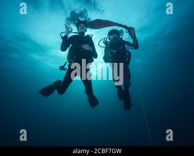 Junge Frau und Mann Taucher warten auf Sicherheitsstopp. Unterwasser Sport und Freizeit Aktivitäten. Stockfoto