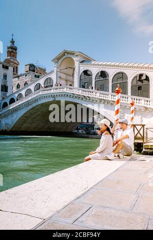 Venedig Italien Paar Männer und Frauen auf einer Städtereise nach Venedig, Männer und Frauen am Wasser mit Blick auf die berühmte Rialtobrücke in Venedig Italien Stockfoto