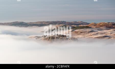 Panoramablick auf die wunderschöne Wolkeninversion, die bei Sonnenaufgang von den hängen des Ben Cruchan beobachtet wird, während die Hügel über Loch Awe aus dem Meer des Clos hervorgehen Stockfoto