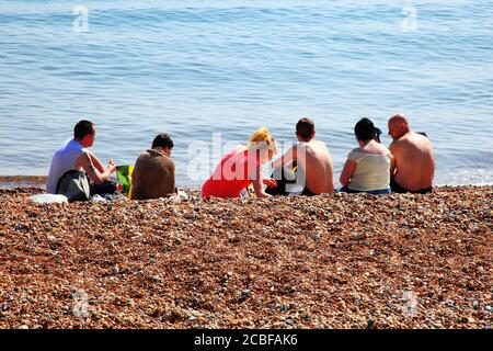 Hastings, Vereinigtes Königreich, Apr 28, 2011 : EINE Gruppe von Urlaubern, die an einem Kieselstrand in Hastings East Sussex sonnenbaden, ist eine beliebte Reise de Stockfoto