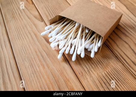 Wattestäbchen aus Holz und Baumwolle. Umweltfreundliche Ohrstöpsel. Holzhintergrund. Stockfoto