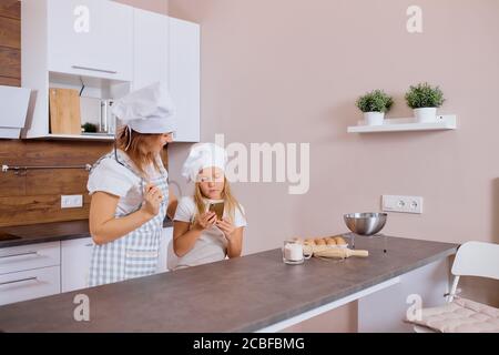 kaukasische Mutter und Tochter stehen zusammen Blick auf Smartphone, auf der Suche nach delicipus Rezept der Kuchen, auf der Suche, Tragen Schürze Stockfoto