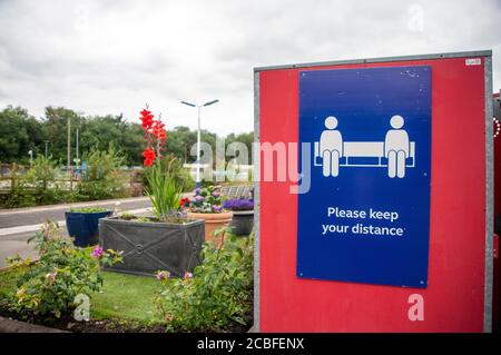 Blau und weiß ‘Bitte halten Sie Ihre Entfernung’ Poster an einer roten Anzeigetafel am Bahnhof Wigan Wallgate während einer lokalen Sperre befestigt. VEREINIGTES KÖNIGREICH Stockfoto