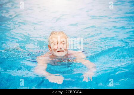 Kaukasische gesunde ältere Schwimmen im Schwimmbad für Entspannung Im Sommer Urlaub Aktivität Stockfoto