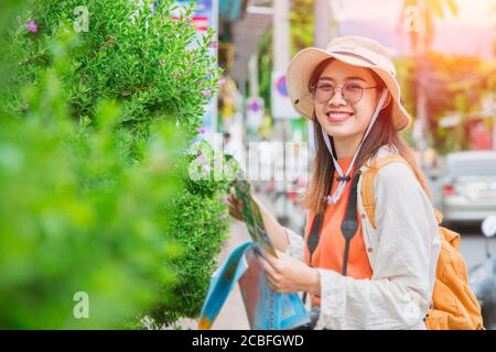 Asiatische Reisende Mädchen Teenager oder Tourist glücklich Lächeln reisen in Sommerurlaub mit Karte zu Fuß an der Straße Stockfoto