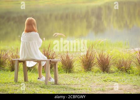 Einsames Kind Mädchen blonde Haare sitzen an ruhigen Frieden See Allein am Morgen Rückansicht Stockfoto