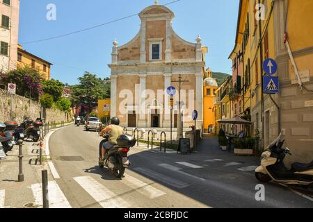 Ein Mann auf einem Motorroller auf der Straße vor der Kirche des Heiligen Franziskus in der alten Seestadt, Lerici, La Spezia, Ligurien, Italien Stockfoto