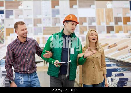 Angenehme Lagerarbeiter froh, Kunden zu helfen, baten sie um Beratung, Arbeiter lieben seinen Job, er ist sozial angepasst Stockfoto