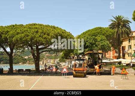 Resurfacing der Straße an der Strandpromenade mit rat Arbeiter bei der Arbeit und Touristen zu Fuß im Sommer, Lerici, La Spezia, Ligurien, Italien Stockfoto