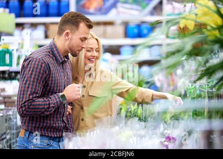 Frau shopaholic kam, um Kauf mit Ehemann zu machen, Paar kaufen Pflanzen in Töpfen, genießen Sie den Einkauf. Grüne Pflanzen und Blumen für ihre neue Wohnung Stockfoto