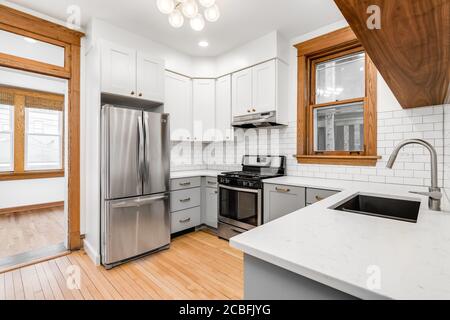 CHICAGO, IL, USA - 20. MAI 2020: Eine kleine Küche in einer Downtown-Wohnung mit weißen U-Bahn-Fliesen und weißen und grauen Schränken. Stockfoto