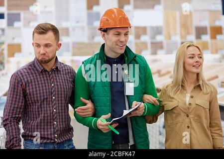 Angenehme Lagerarbeiter froh, Kunden zu helfen, baten sie um Beratung, Arbeiter lieben seinen Job, er ist sozial angepasst Stockfoto