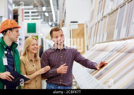 Lustige Unterhaltung von Lagerarbeiter und Kunden, sie reden miteinander, haben Spaß auf dem Markt, Arbeiter helfen Stockfoto