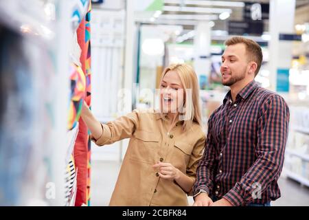 Ehepaar einkaufen, Frau wie bunte Kissen und Bettdecken auf dem Markt, Mann aussehen und stimmen mit ihr Stockfoto